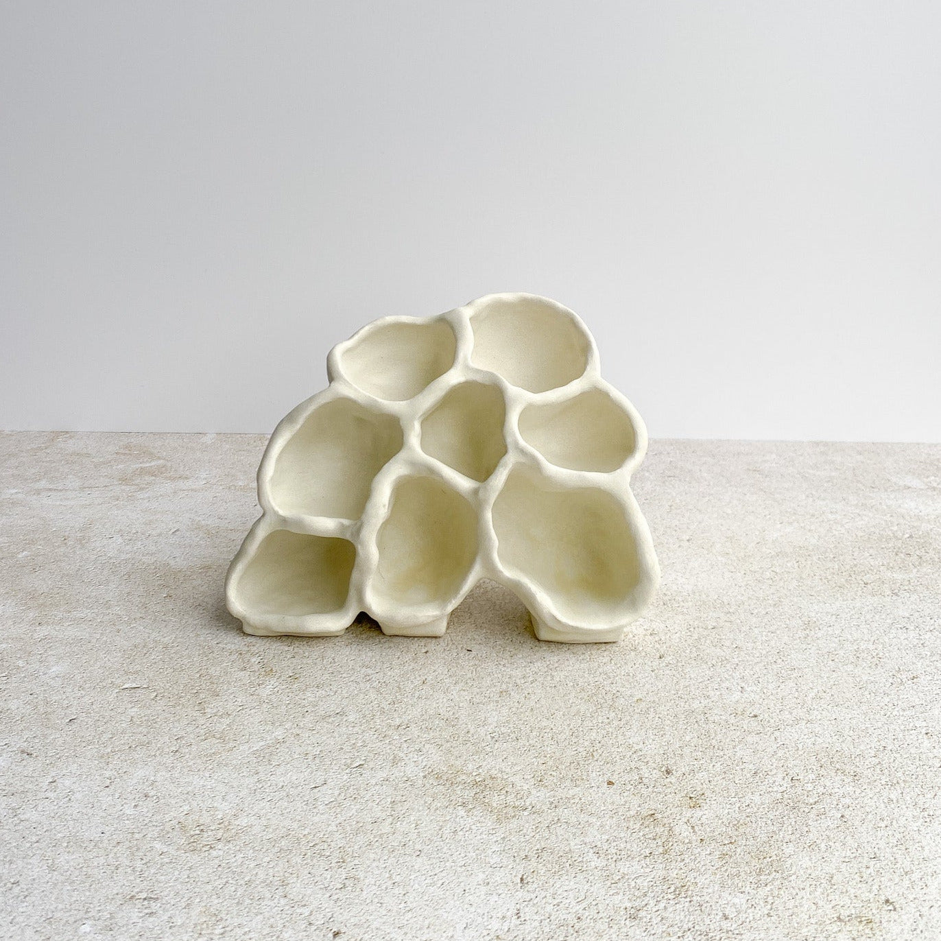 White ceramic honeycomb-shaped ceramic object on a light gray surface