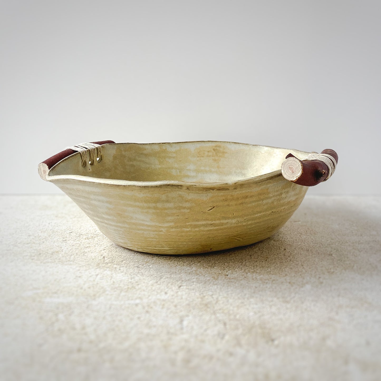 Bowl with wooden handles on a textured surface