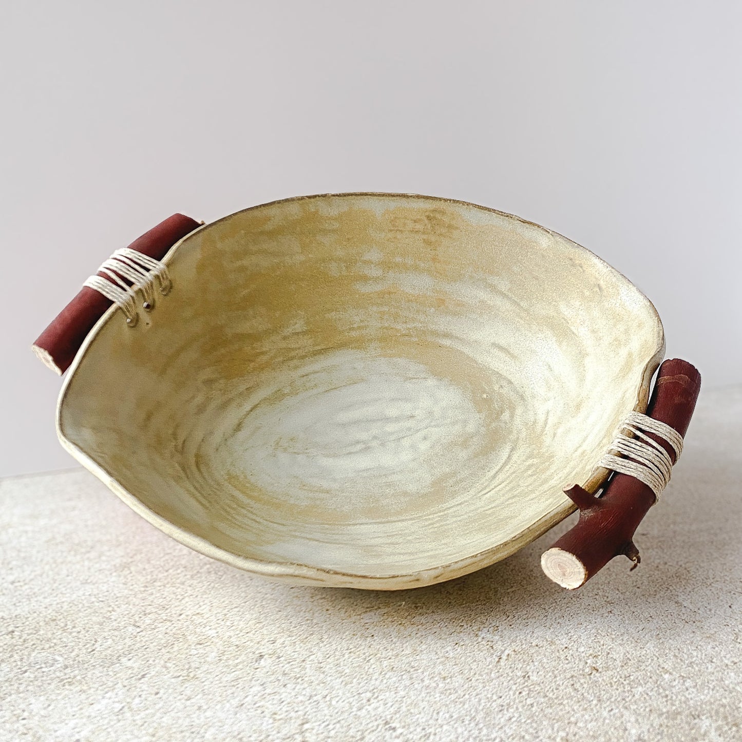 Ceramic bowl with wooden handles on a textured surface
