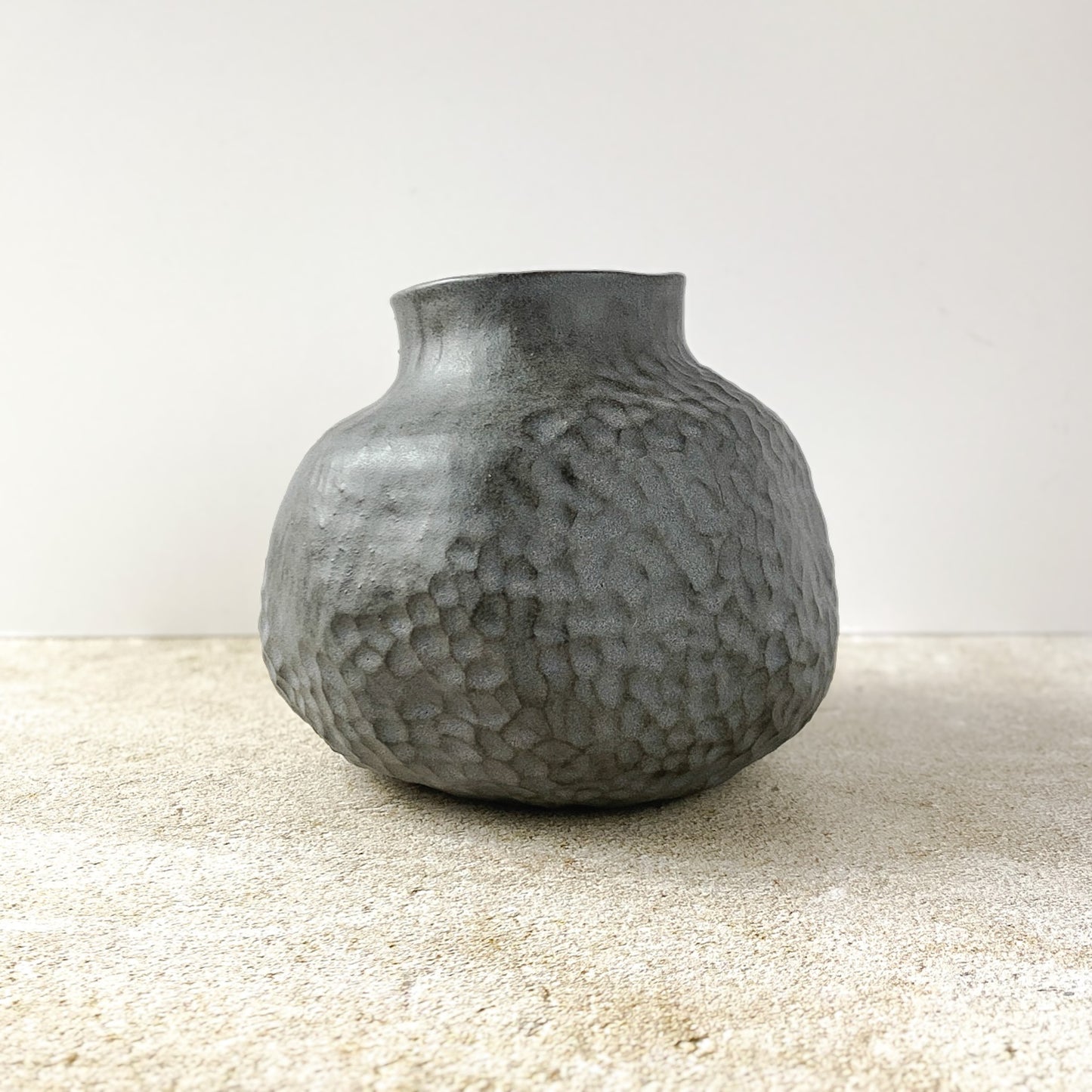 Textured gray vase on a light surface with a neutral background