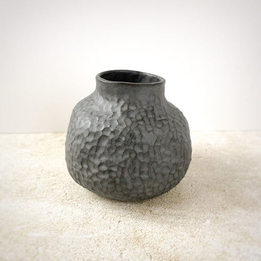 Textured gray ceramic vase on a light surface with a neutral background