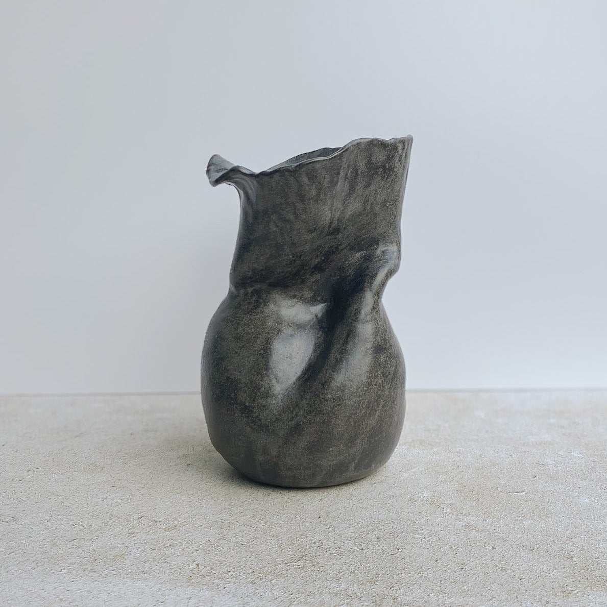 Gray ceramic vase on a white surface with a neutral background