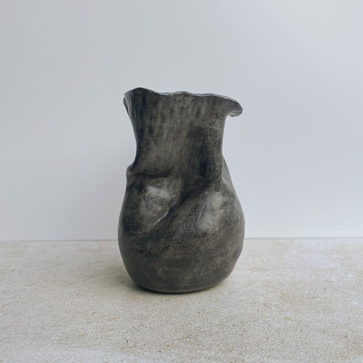 Gray ceramic vase on a white surface with a neutral background