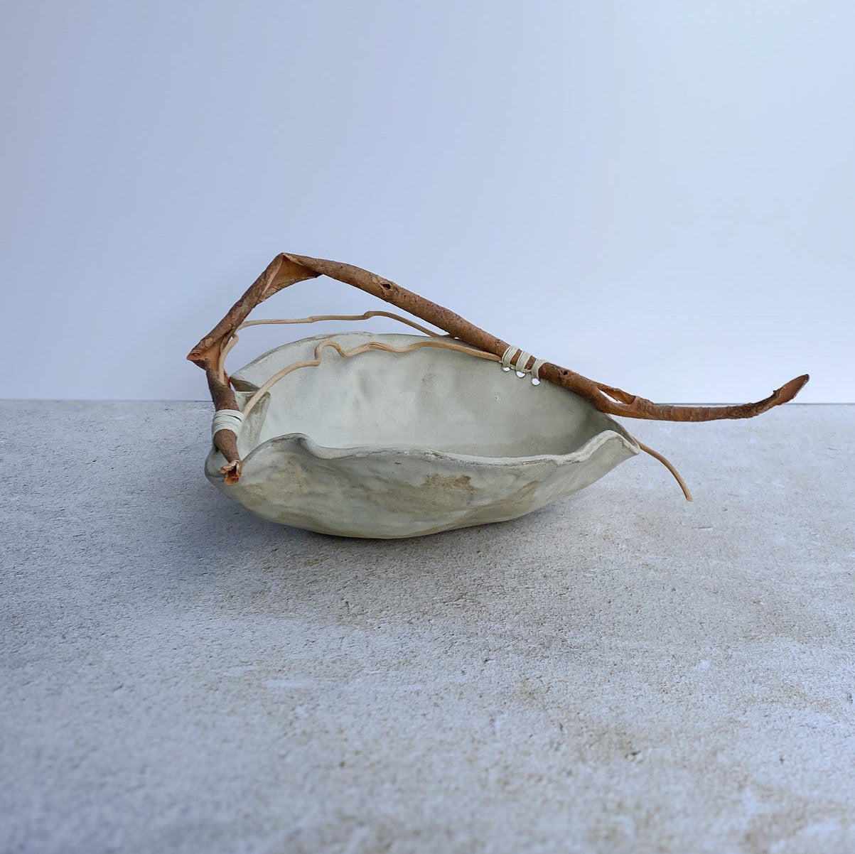 Small ceramic dish with a branch on a light surface