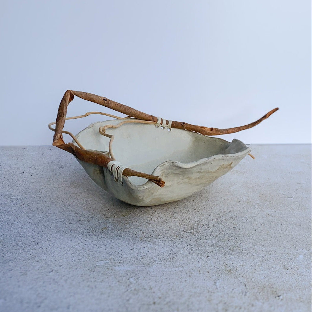 Ceramic bowl with natural branch on a light gray surface