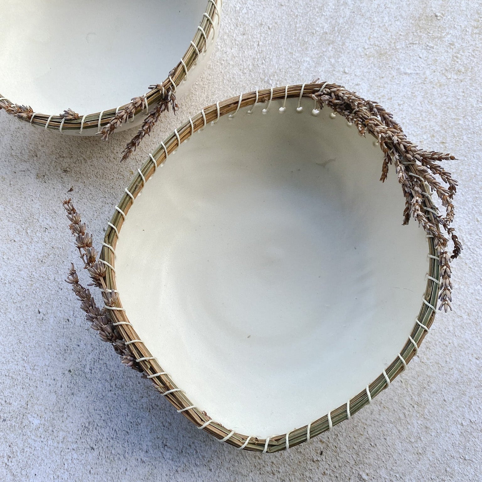 Ceramic bowl with dried lavender around the rim on a light textured background