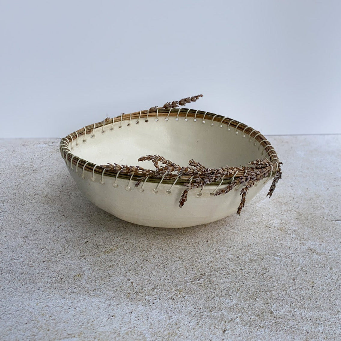 Small ceramic bowl with decorative dried lavender rim on a textured surface