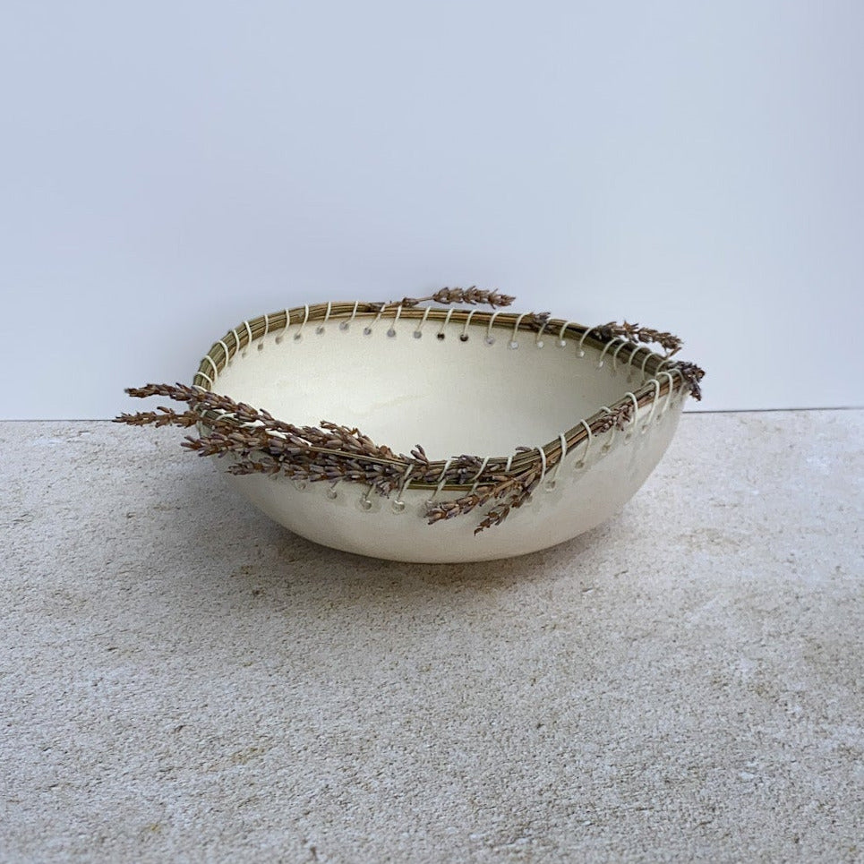 Small ceramic bowl with decorative dried lavender rim on a textured surface