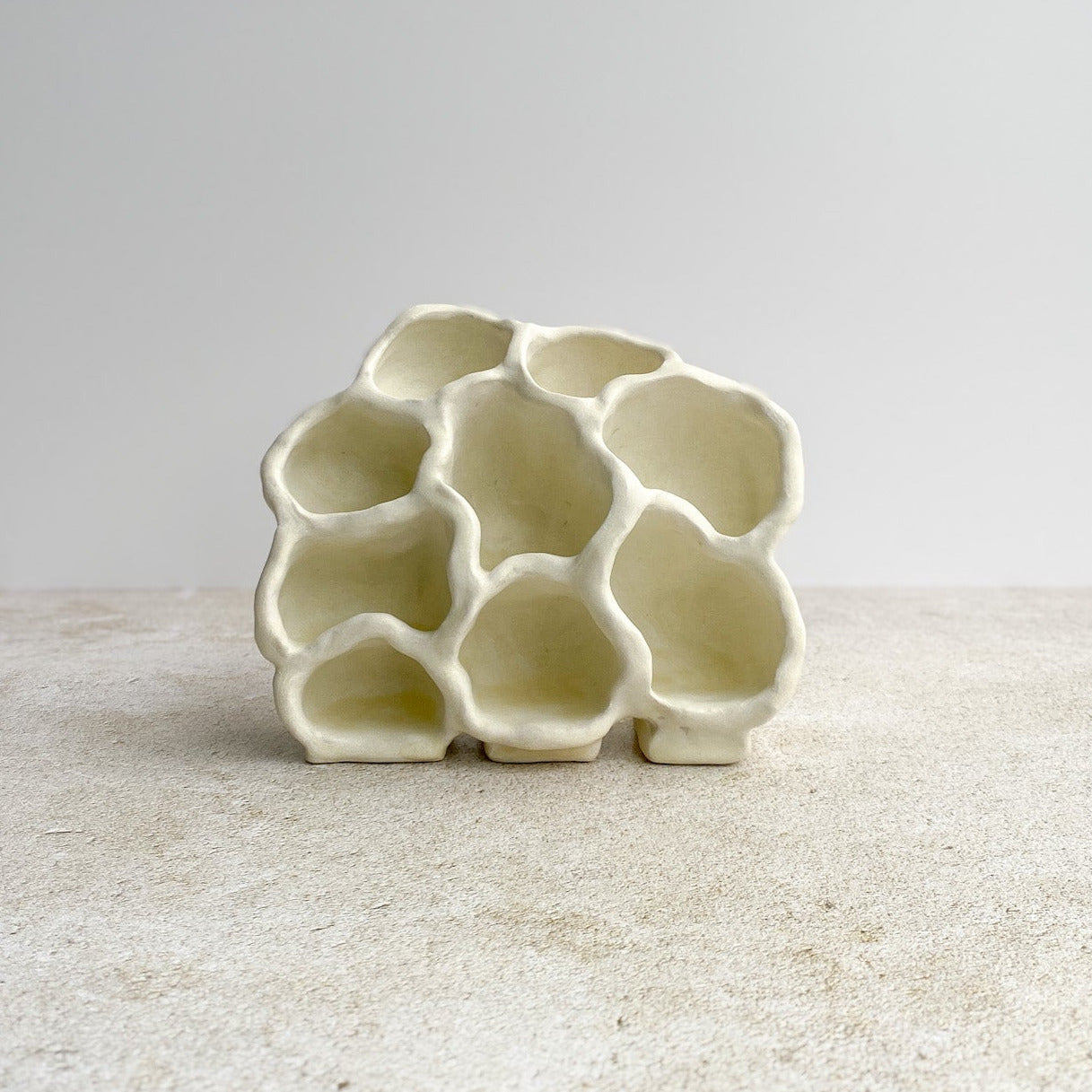 White ceramic object with an organic form on a light gray background