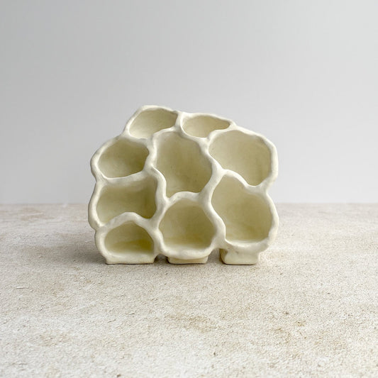 White ceramic object with an organic form on a light gray background