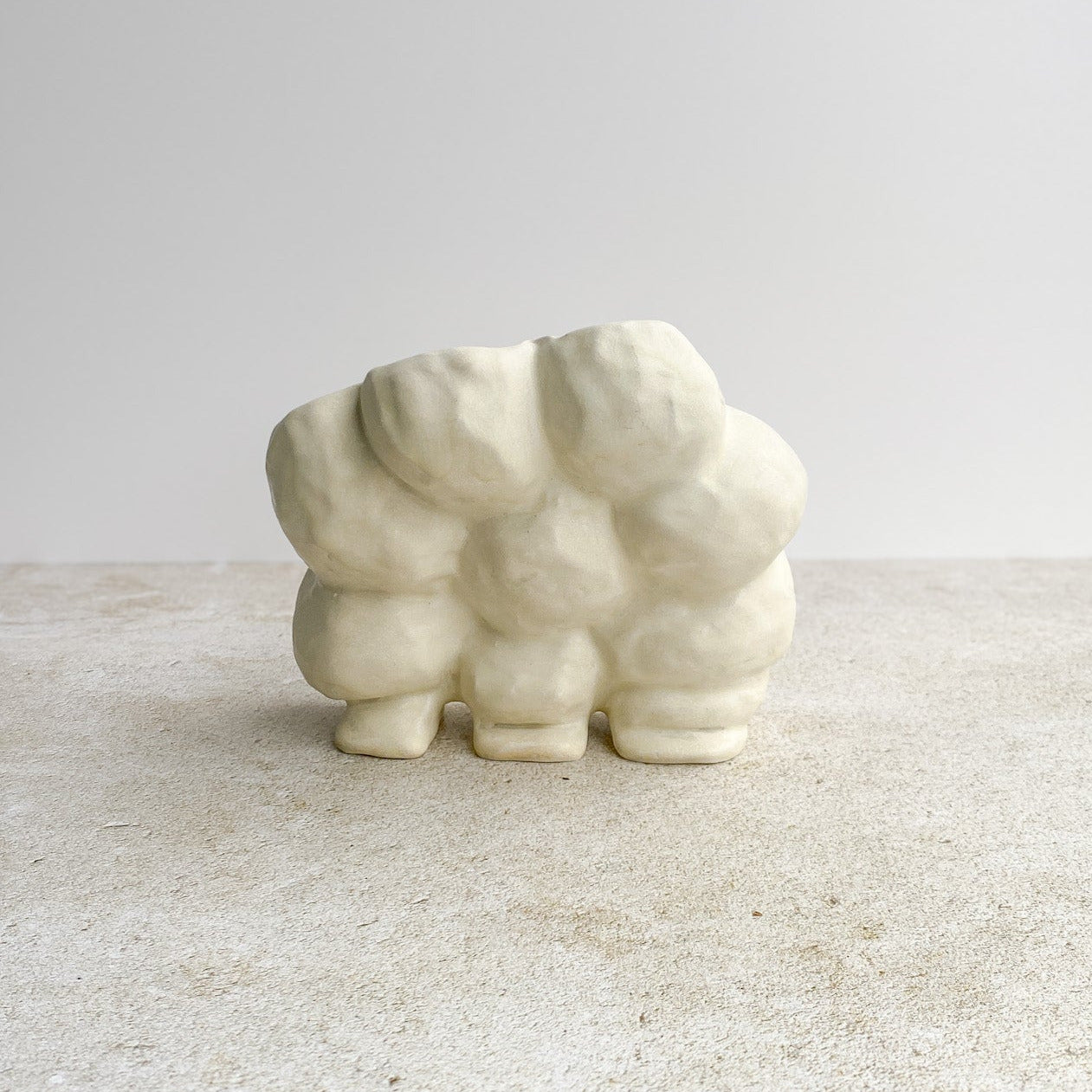 White ceramic object with a textured surface on a light gray background