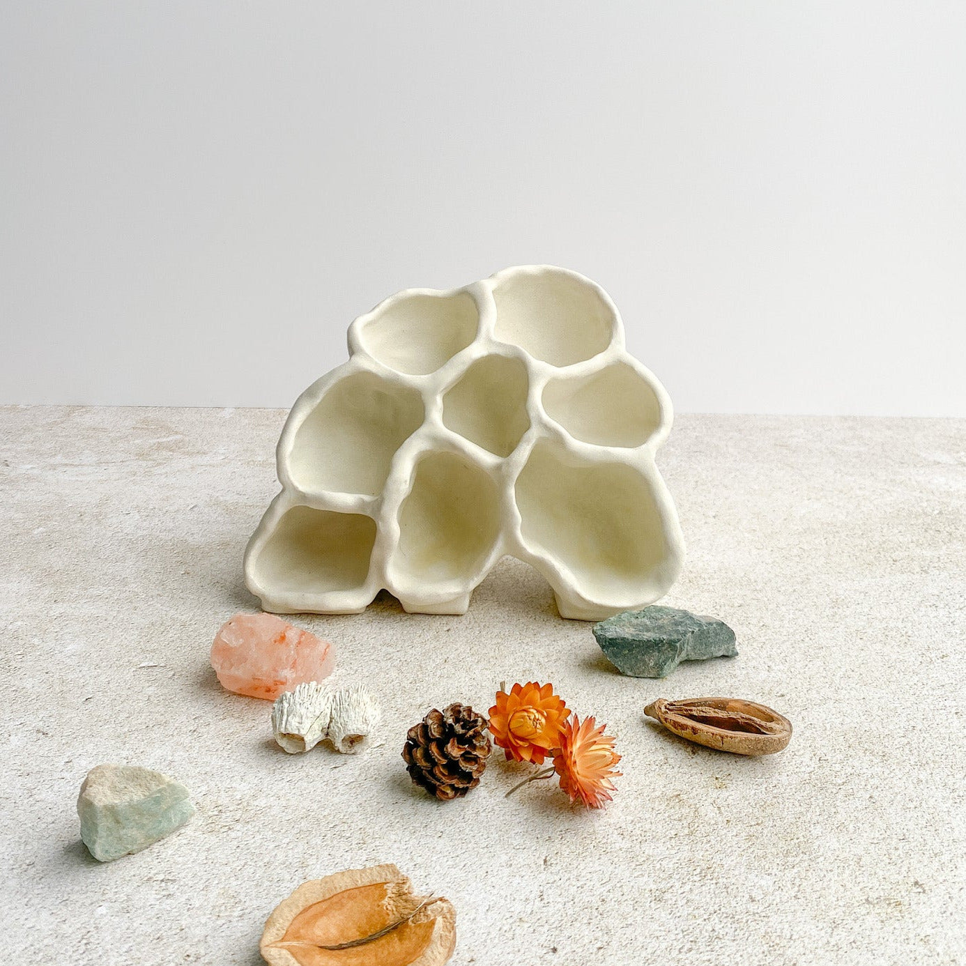 White ceramic ceramic sculpture with small decorative items on a light surface