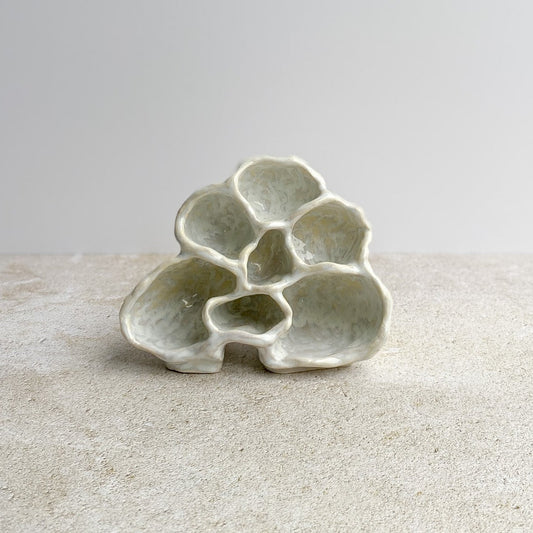 Ceramic sculpture on a textured surface with a plain background