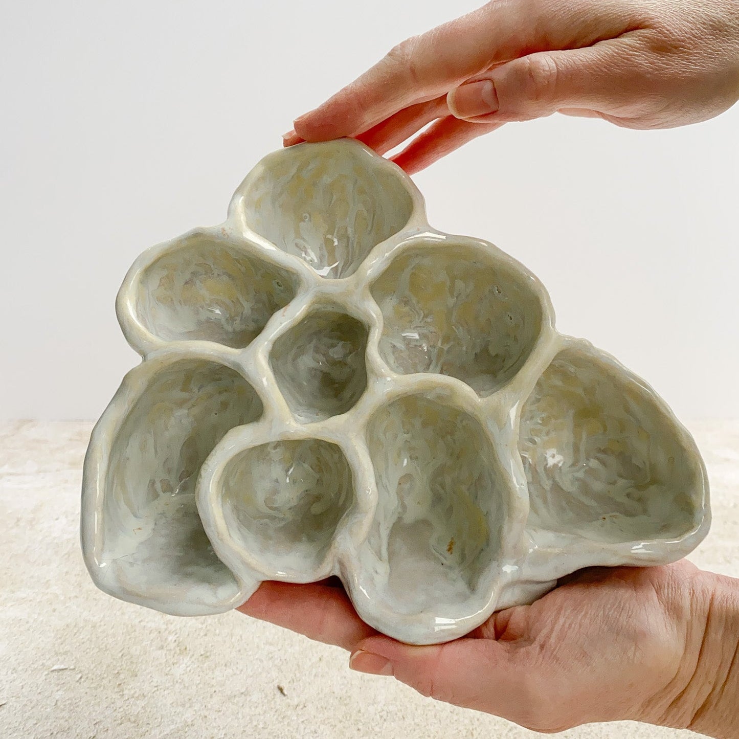 Ceramic object held by a hand on a neutral background