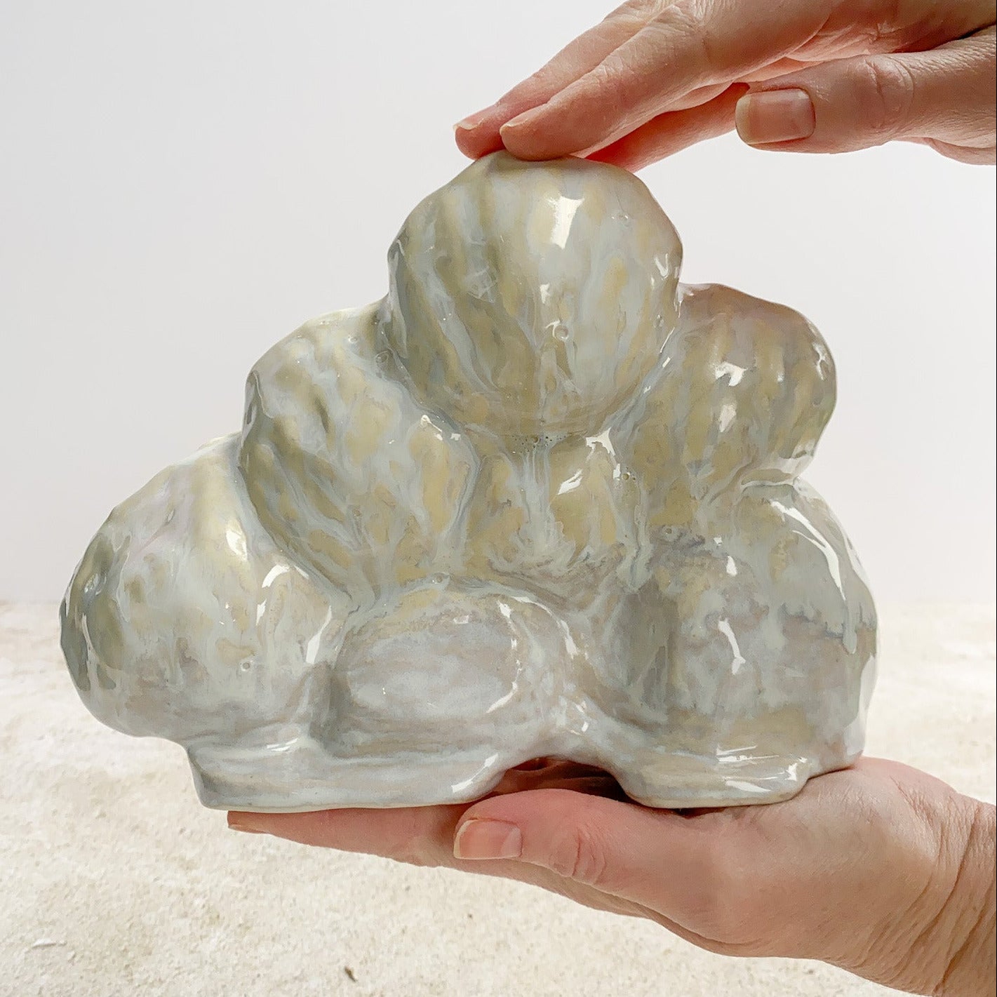 Hand holding a large, textured ceramic piece against a neutral background