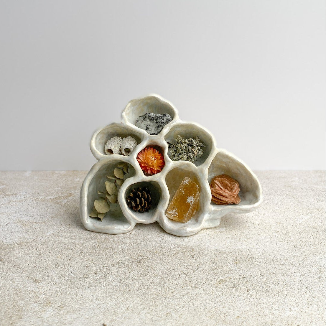 Decorative ceramic piece with small compartments on a textured surface