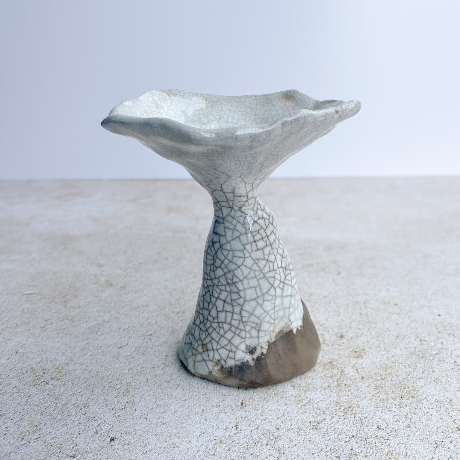 Ceramic mushroom sculpture with textured surface on a sandy background