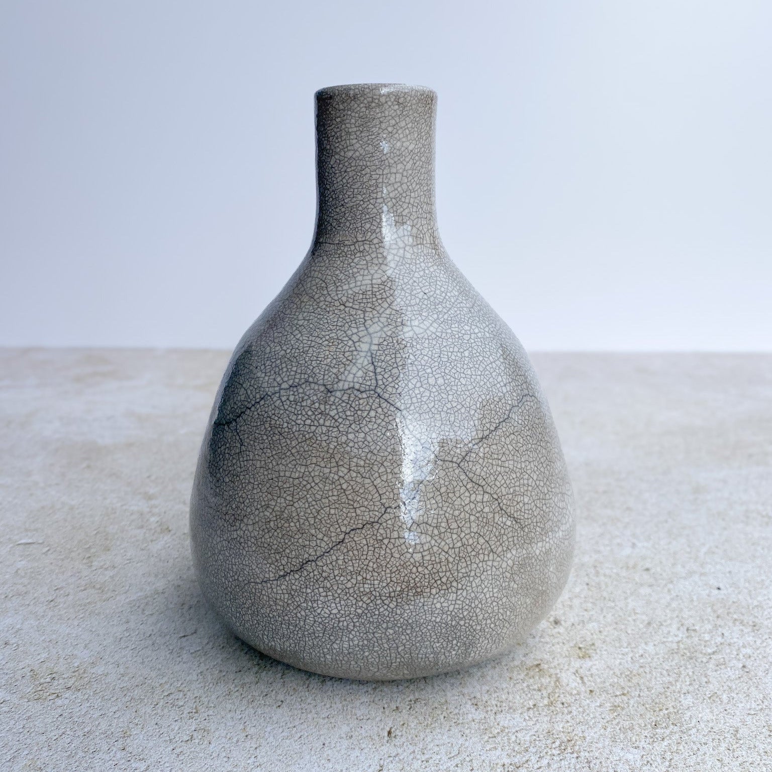 Crackle ceramic raku vase on a light surface with a neutral background