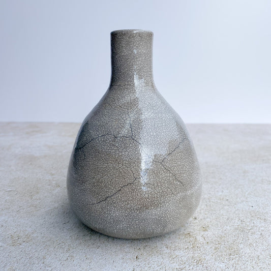 Crackle ceramic raku vase on a light surface with a neutral background