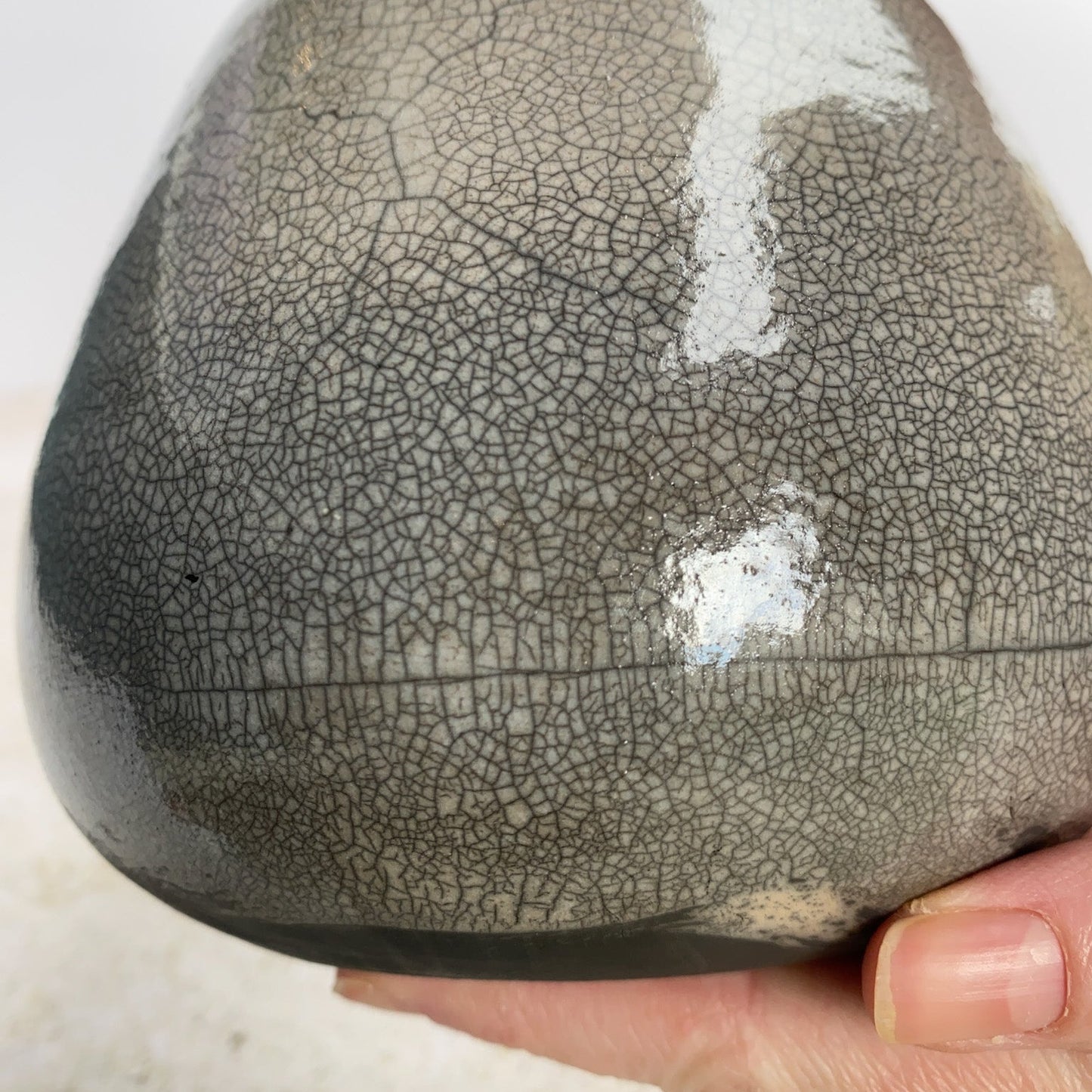 Hand holding a ceramic vase with a crackle surface