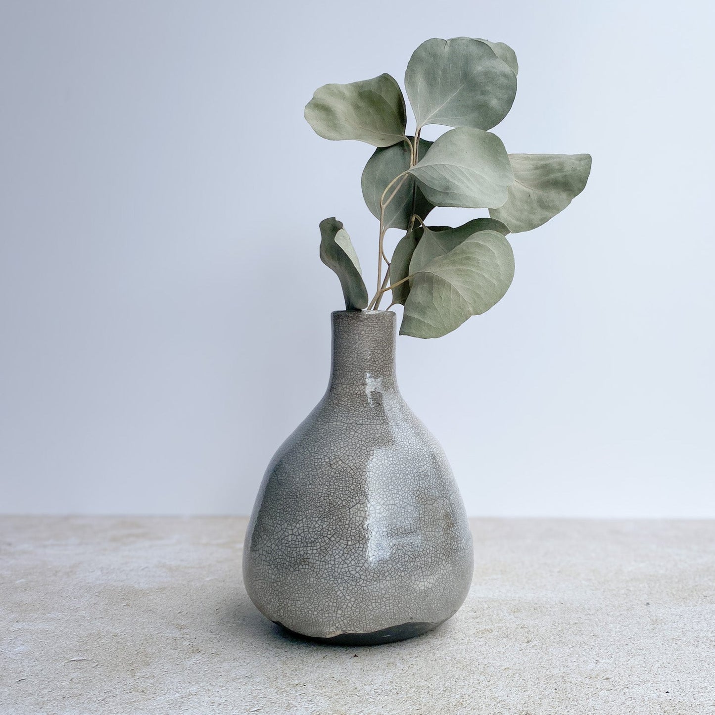 Black and white raku ceramic vase with eucalyptus on a textured surface