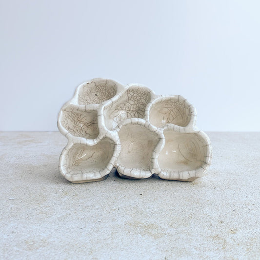 Ceramic organic-shaped object on a light surface with a white background