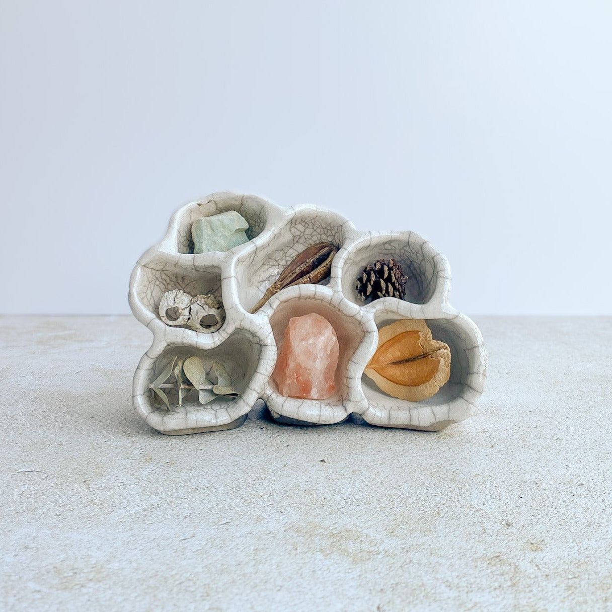 Ceramic shell-shaped trinket dish with small stones on a white background