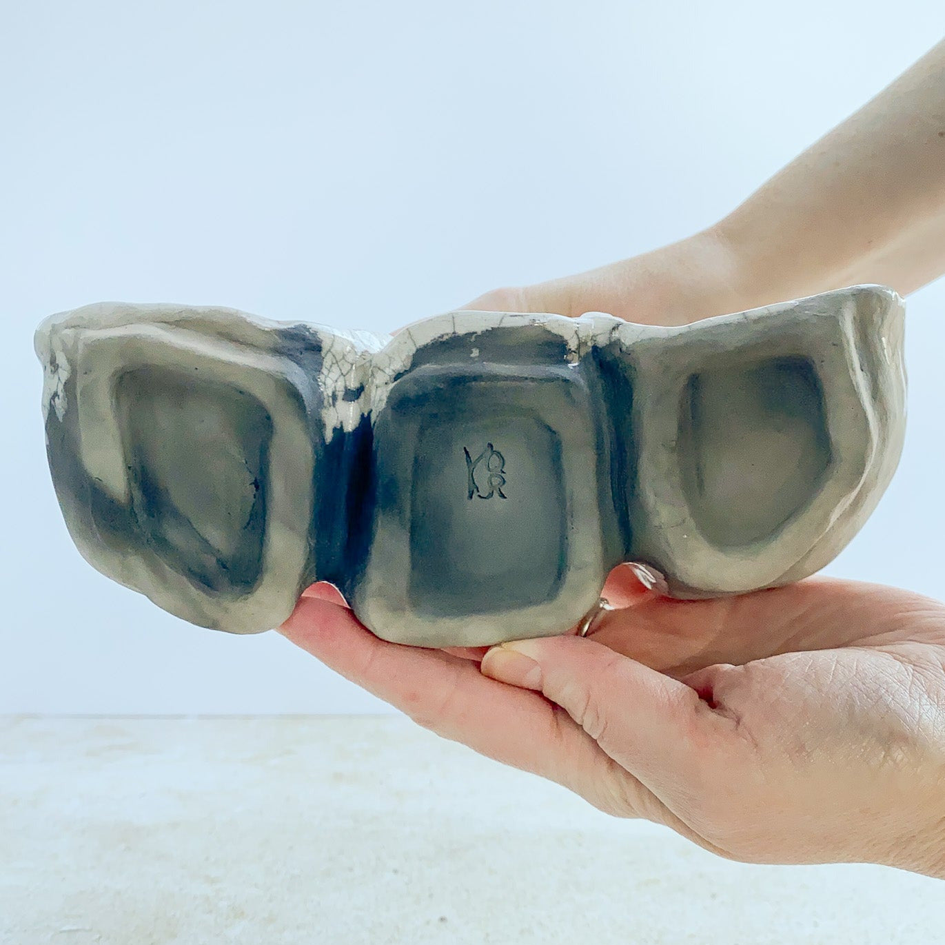Hand holding a ceramic sculpture against a light background