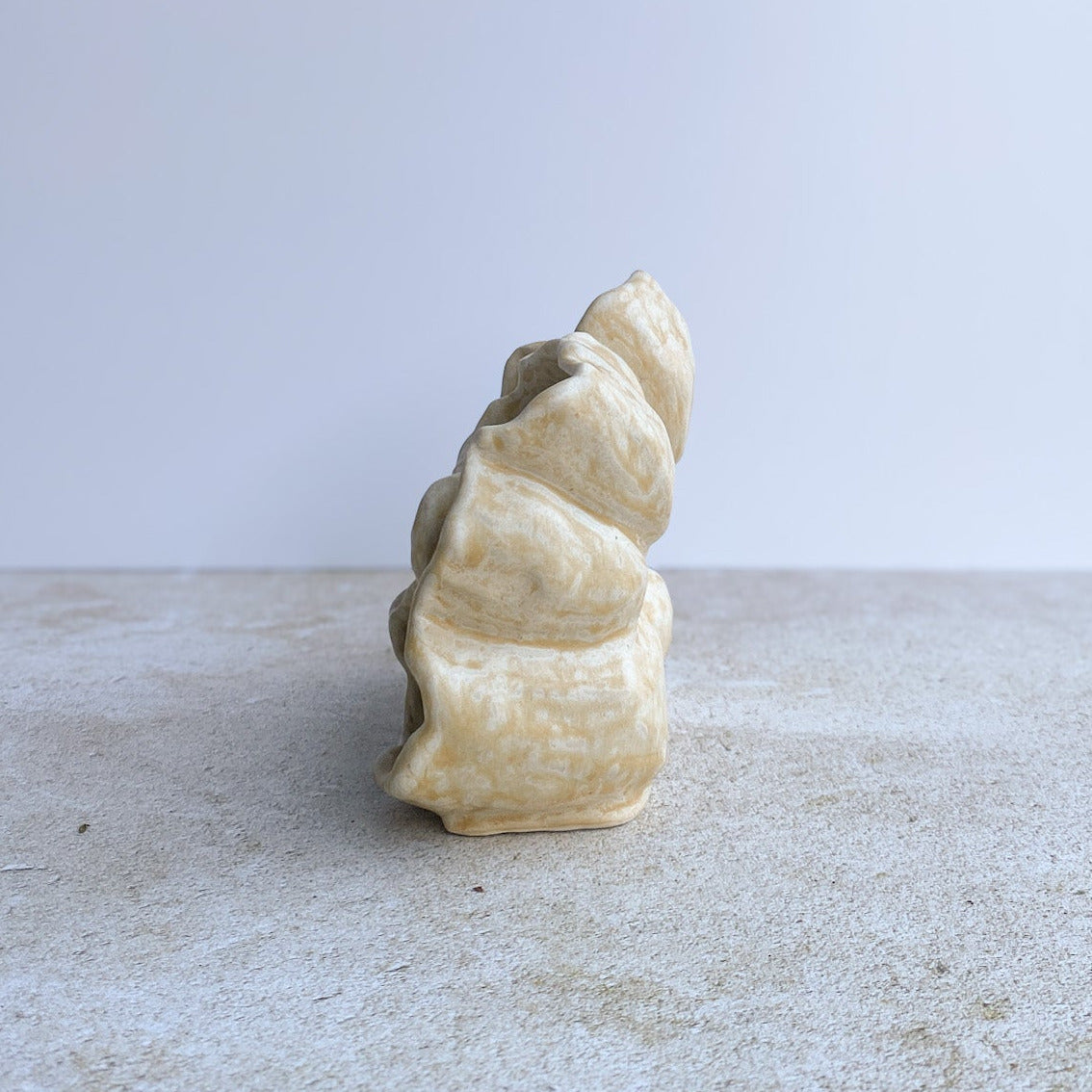 Decorative ceramic sculpture on a textured surface with a light gray background