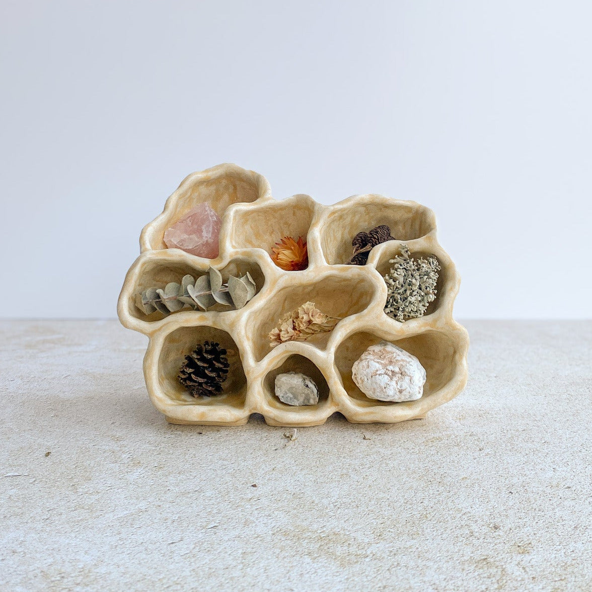 Decorative ceramic holder with natural elements on a textured surface