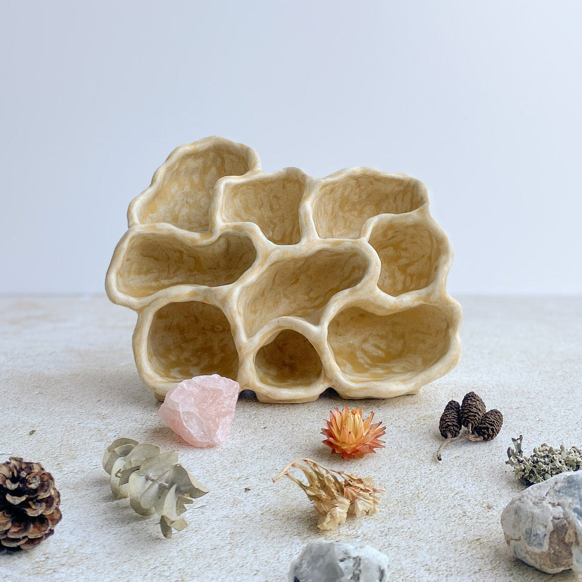 Decorative coral-like ceramic object on a white surface with small decorative items around it.