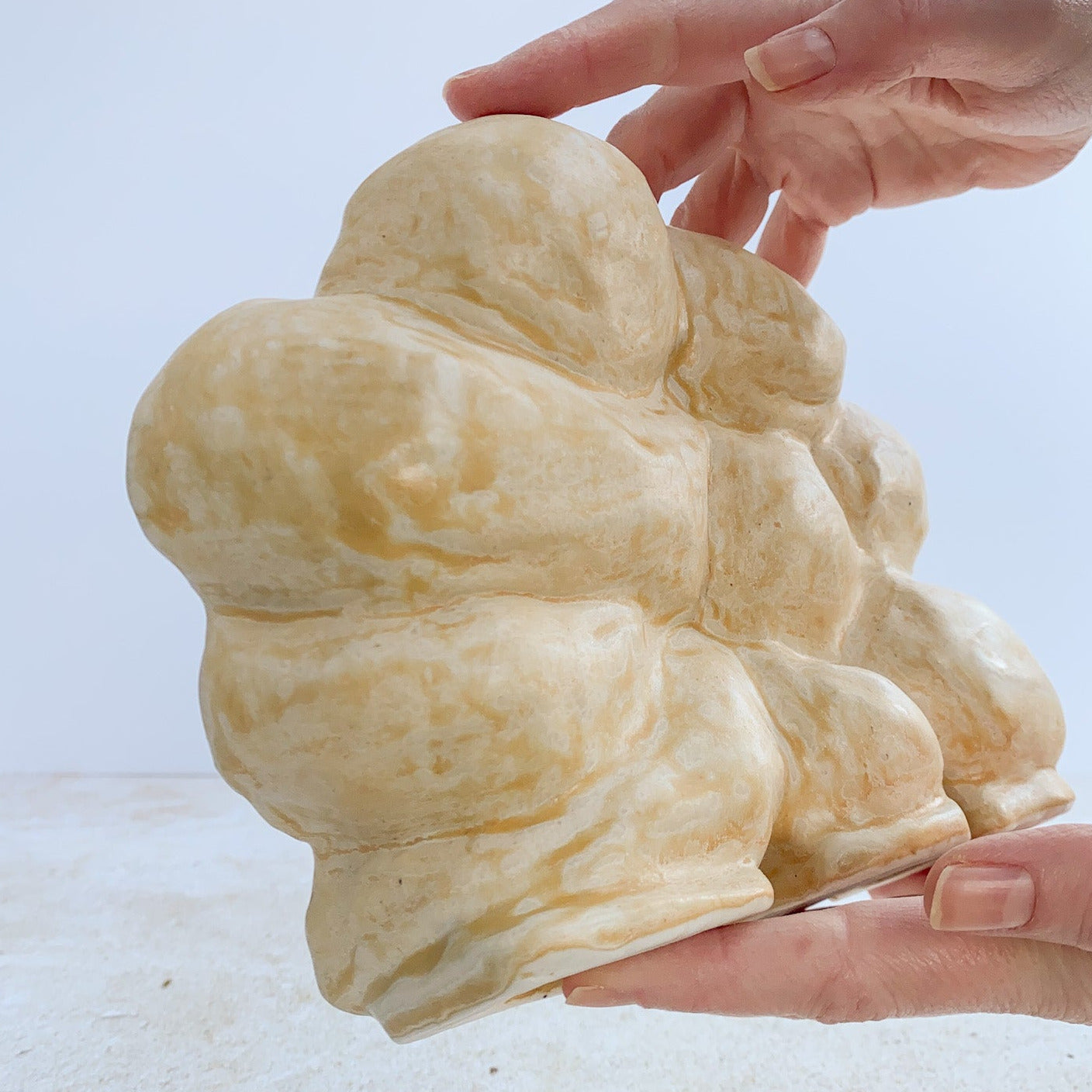 Hand holding a ceramic sculpture on a light background