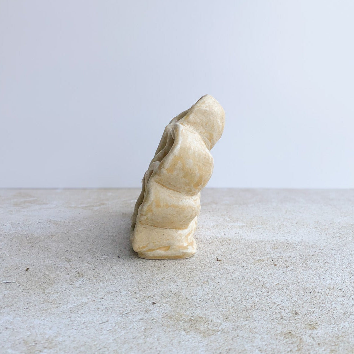 Ceramic sculpture on a light gray surface with a white background
