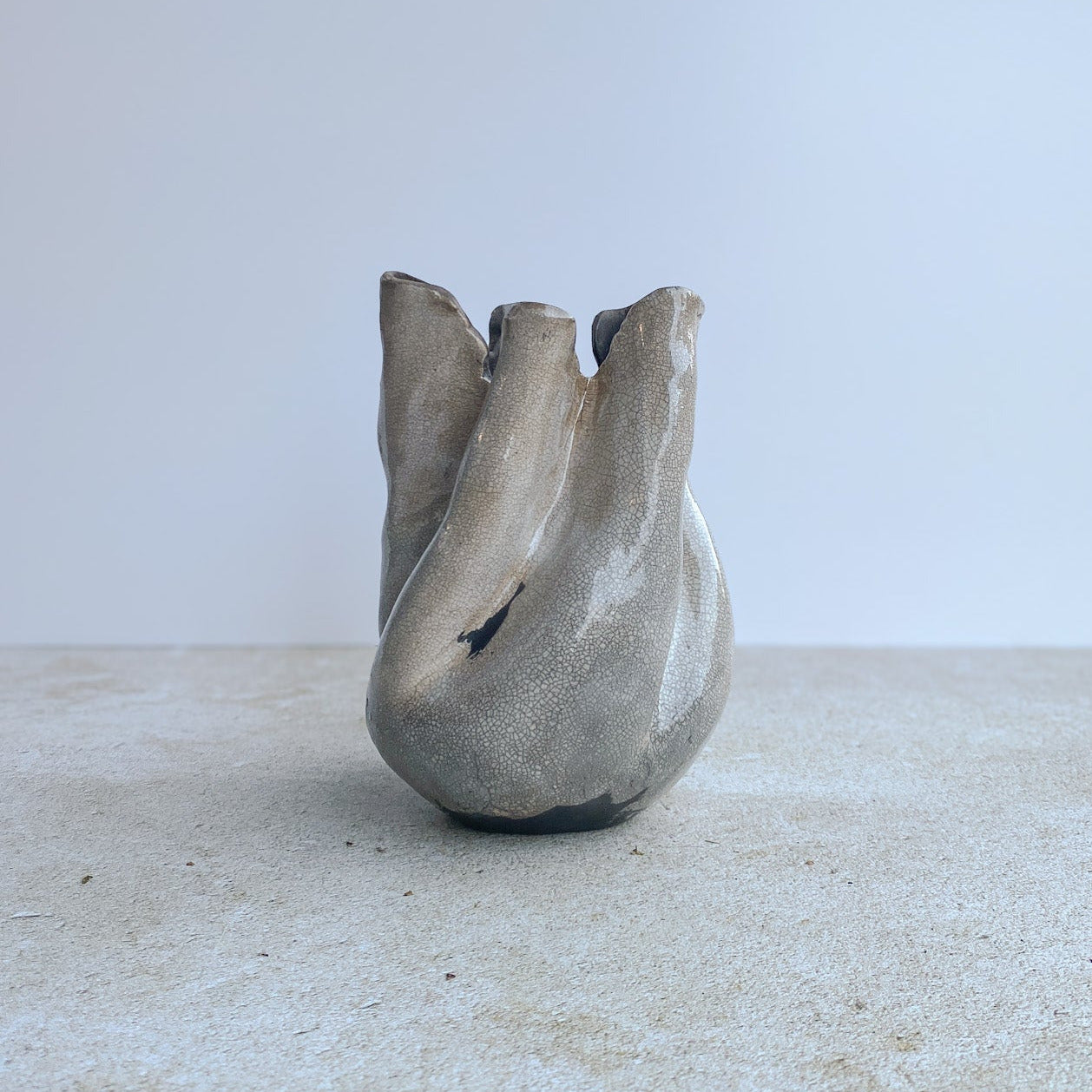 Ceramic raku vase with an organic form on a light surface