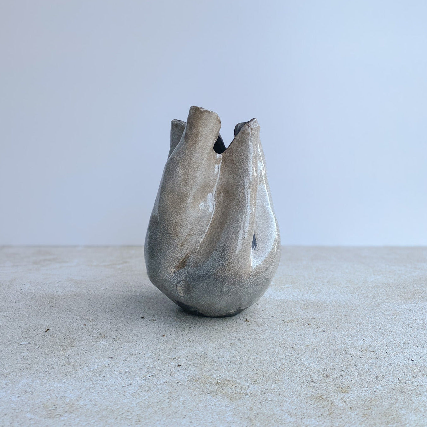 Abstract ceramic sculpture on a textured surface with a light background