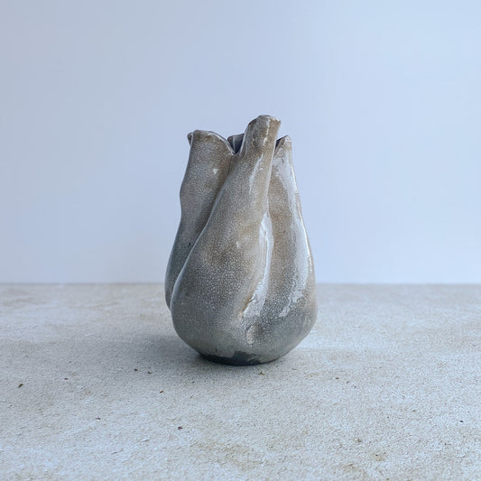 Ceramic raku vase with an organic design on a light surface with a white background