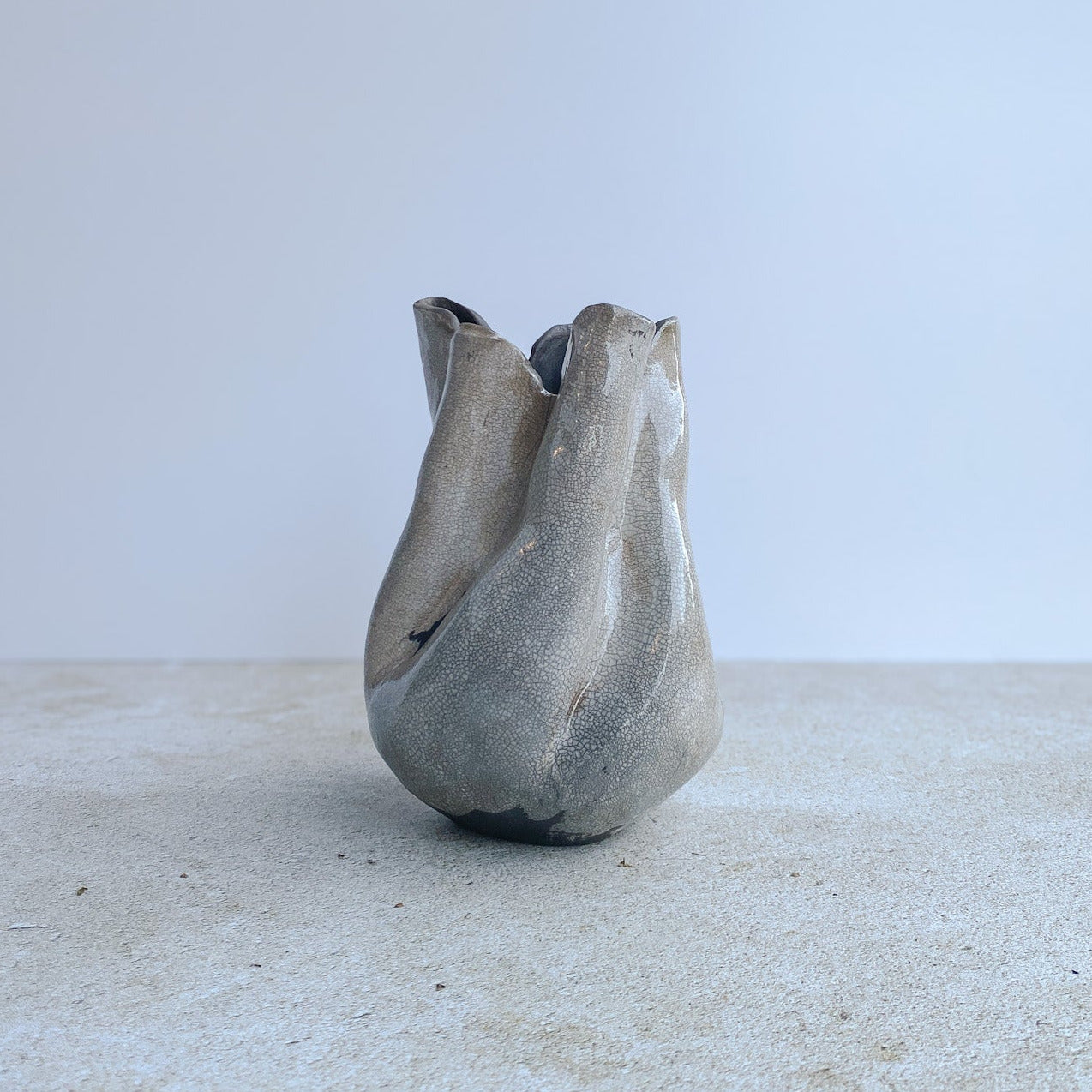 Raku ceramic vase on a textured surface with a white background