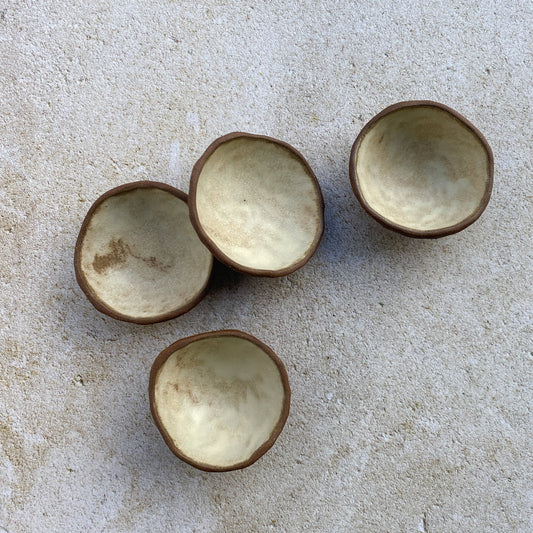 Four ceramic bowls on a textured beige surface
