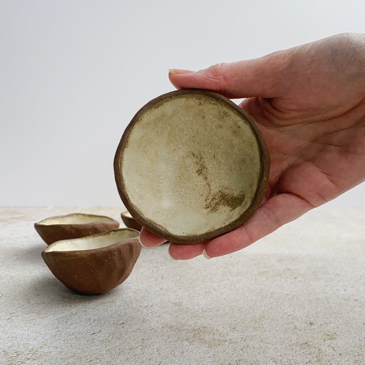 Hand holding a small ceramic bowl against a light background