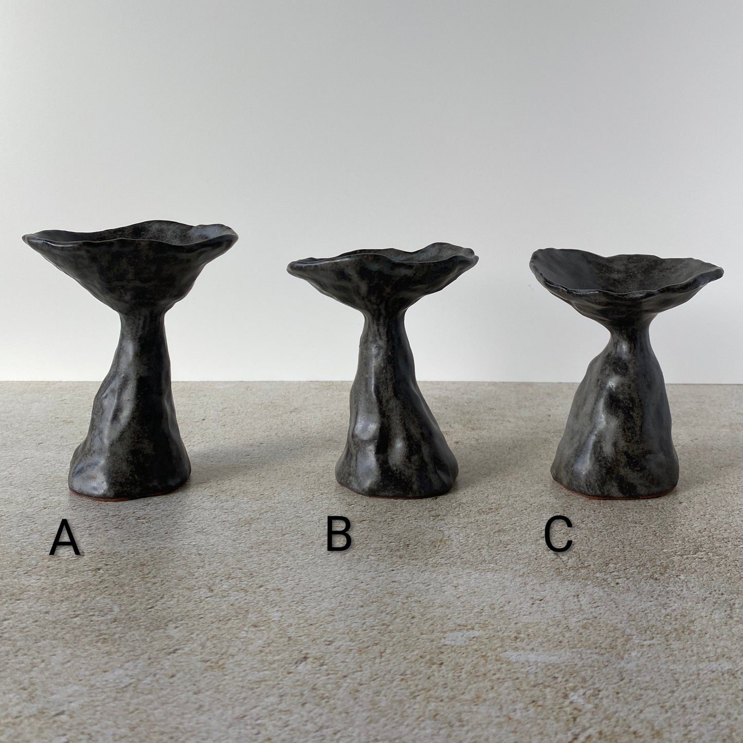 Three ceramic toadstools on a gray surface with a white background