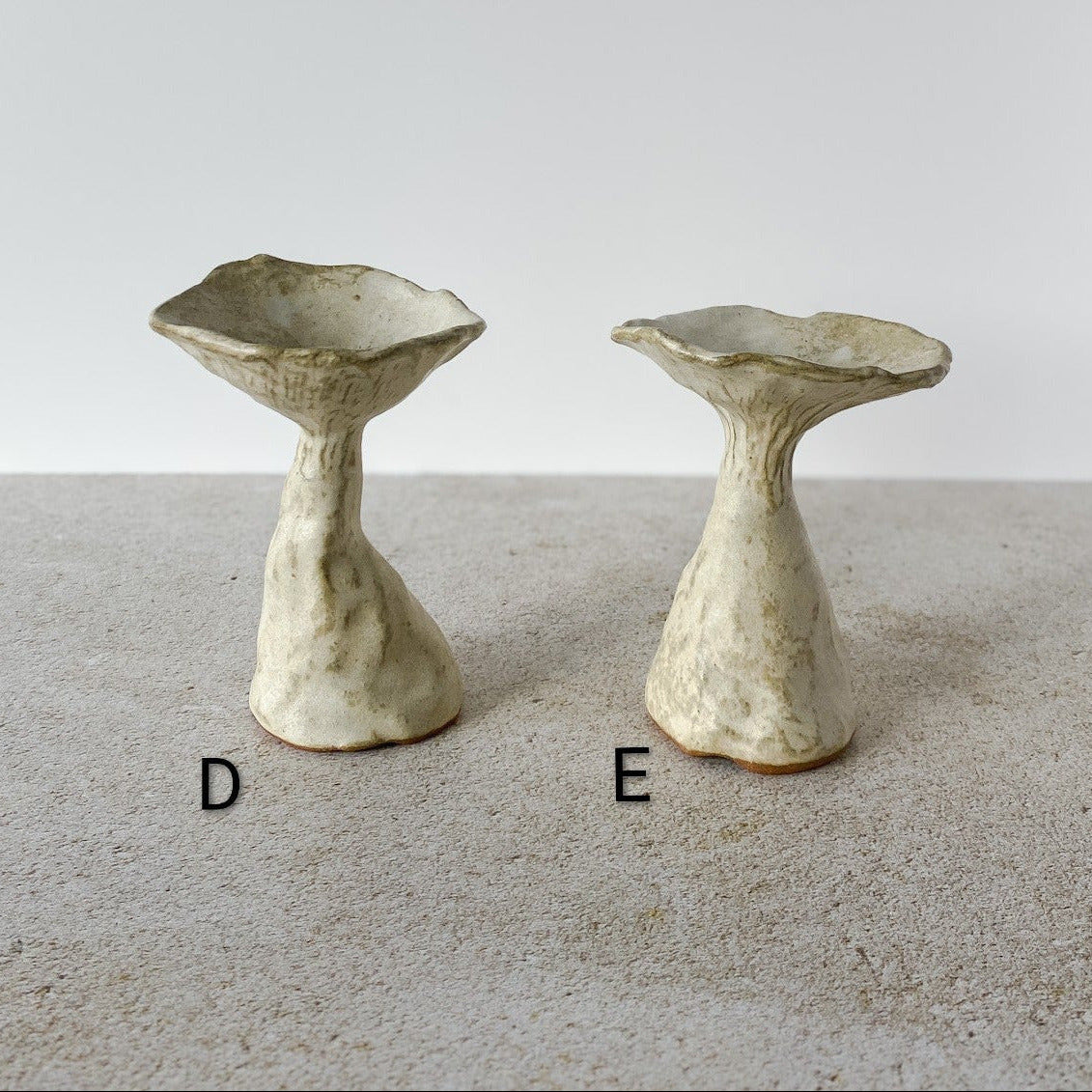 Two unique ceramic mushrooms on a neutral background